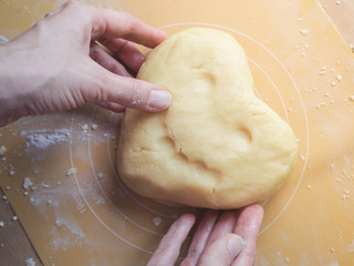 Heart of dough in the hands of a young lady.
