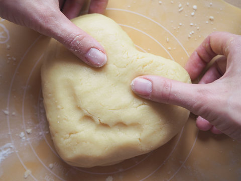Heart of dough in the hands of a young lady.
