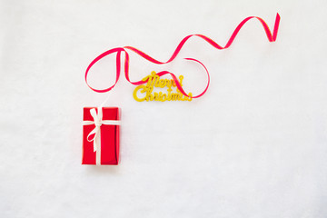 small red gift box and gold merry christmas text with red ribbon