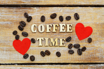 Coffee time written with wooden letters on rustic surface, two red hearts and coffee beans
