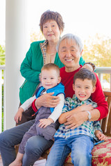 Obraz premium Senior Adult Chinese Couple Sitting With Their Mixed Race Grandchildren