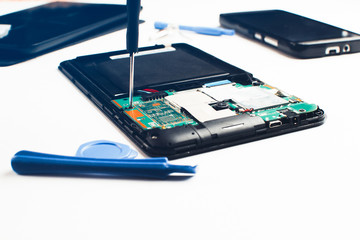 On the table the tablet is disassembled and tools