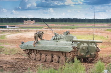 Fototapeta premium Combat Vehicle of the Airborne at the training field near the Moskow. Tank on the field with blue sky and heavy clouds. soldier in full ammunition on the armor. Climbs inside the machine