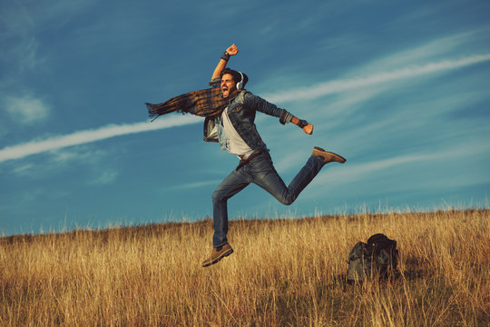 Young happy man jumping into the air in the meadow