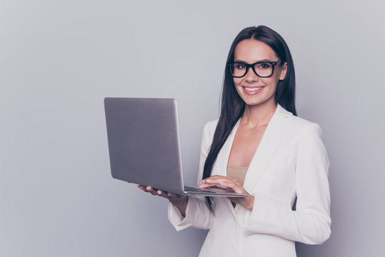 Portrait of caucasian feminine charming lovely cute expert business lady in smart outfit, standing on pure background with pda, beaming smile, touches keypad, writes an e mail