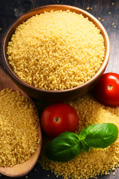 Bowl of uncooked couscous on wooden table
