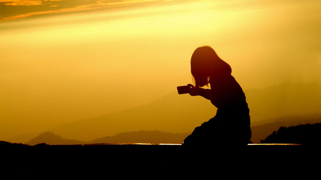 silhouette of woman taking photo with smartphone