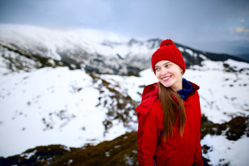 Fototapeta na wymiar Portrait of a smiling happy woman. Shot of a young woman looking at the landscape while hiking in the mountains. Winter hiking