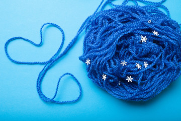 A ball of blue thread for knitting and a heart laid out of a thread.