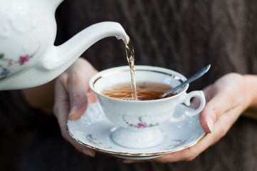 Closeup shot from hands holding a teacup and pouring tea
