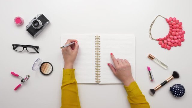 Top View Footage Of Woman Writing In Notebook By Beauty Products