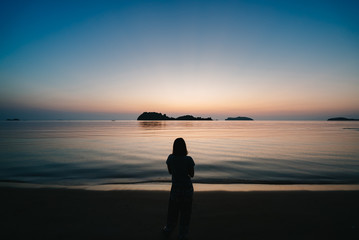 Fototapeta premium Young woman looking up to sunset sky.
