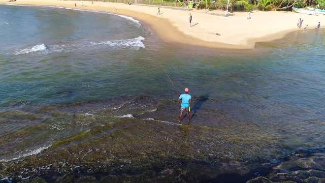 Aerial view of young fisherman that catches fish near the sandy beach in Sei Lanka