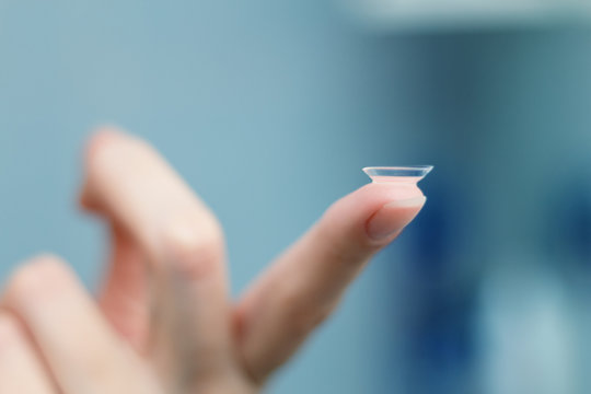 girl holds finger on a contact lens, closeup