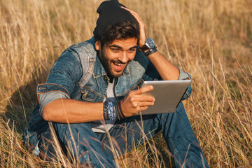 Naklejka na ściany i meble Young man using a digital tablet in nature