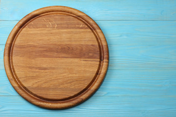 round wooden plate on blue wooden background top view