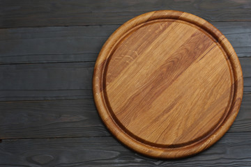 round wooden plate on dark wooden background top view