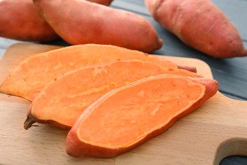 Board with cut sweet potato on wooden table