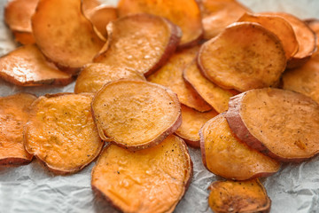 Yummy sweet potato chips on kitchen table, closeup
