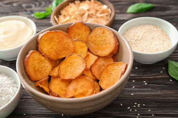Bowl with yummy sweet potato chips on table