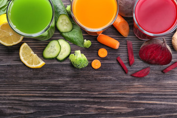 Glasses with various fresh juices and ingredients on table