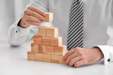 Young man with wooden cubes at table © Africa Studio