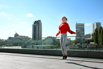 Sporty young woman jumping rope outdoors