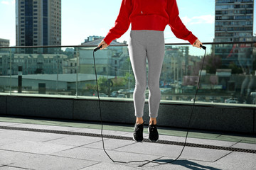 Sporty young woman jumping rope outdoors - Powered by Adobe