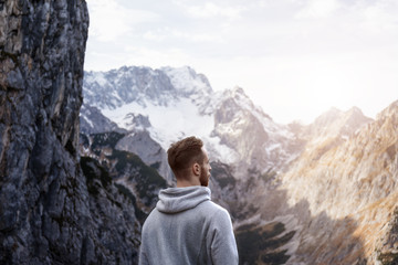 Mann erklimmt Gipfel des Berges und genießt den Sonnenuntergang