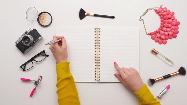 Overhead Top View Of Woman Writing In Notebook By Beauty Products