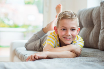 Fototapeta premium Happy schoolboy 9 years old lying on sofa
