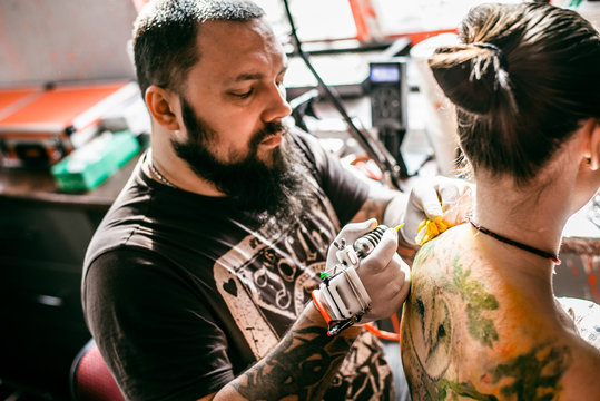 the process of creating a tattoo on the back of a girl