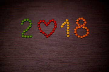 Happy new year 2018 text from colorful candies on wooden background, year of the dog