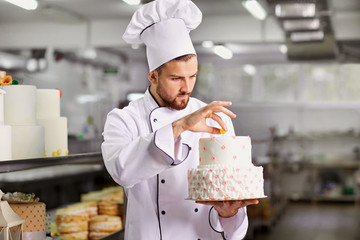 Chef pastry decorates cake in the kitchen.