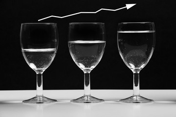 Transparent glasses with water growing business chart.
