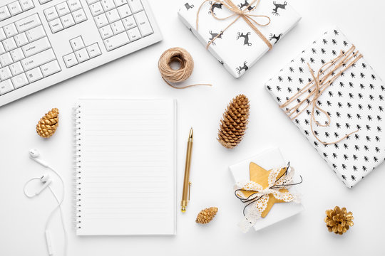 Christmas home office desk with computer, notebook, gifts, branches, christmas gold decorations. Flat lay, top view.