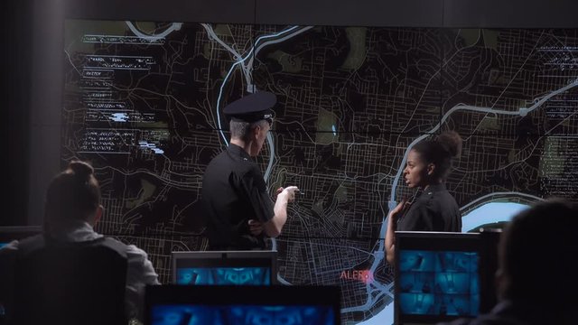 Coworking policemen watching GPS data on electronic map while spying bandit.