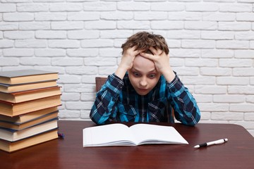 Bored, exhausted and tired student boy ponders over the task solution.  Elementary school,...