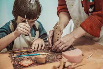 The child is engaged in a pottery school, sculpts a clay product