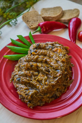 Stewed forest mushrooms cooked with onions and carrots on a red plate with bread and chili