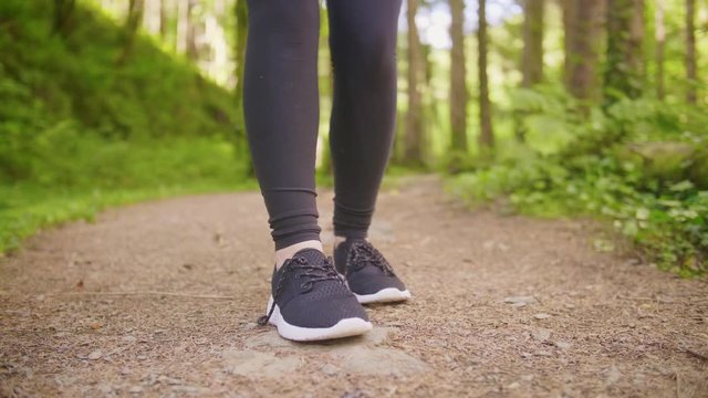 Fit Female Jogger Tying Shoelace On Forest Trail