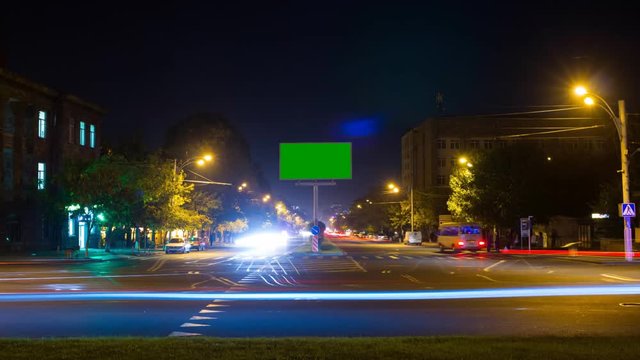 A billboard with a green screen on a background of city traffic with long exposure. Time Lapse.