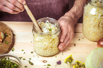 A bank of sauerkraut in the hands of a chef on the background of a table with ingredients. Process...