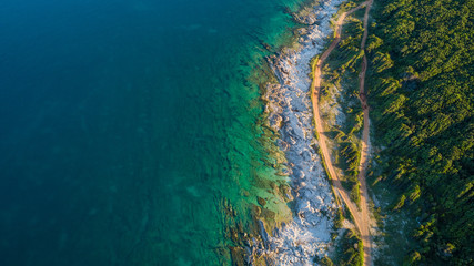 Fototapeta premium Drone shot of a rocky headland at daylight with emerald color water