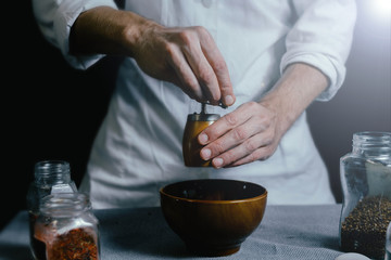 the cook grinds the spices with a hand mill.
