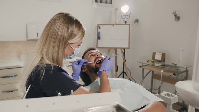 A female dentist treats teeth her patient
