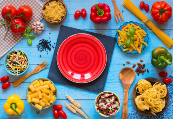 Different types of pasta with various types of vegetables, health or vegetarian concept on a wooden background,  Top view