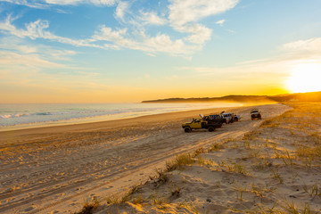 A few cars on a deserted beach at sunset, Queensland, Austraila
