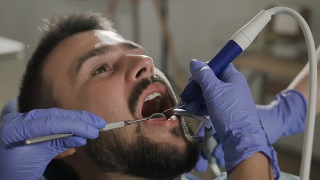 A female dentist and her assistant treats teeth to her patient