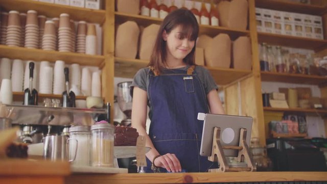 Female Deli Shop Cashier Swiping Card On Digital Tablet Reader